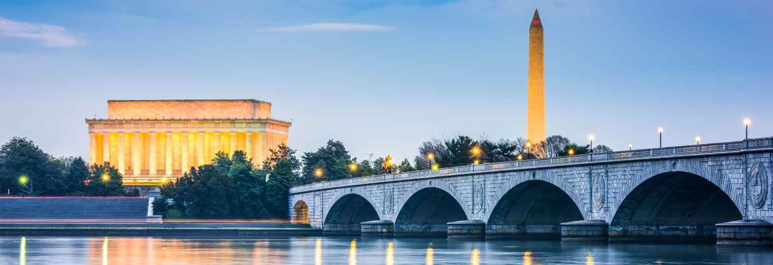 The Lincoln Memorial, Washington Monument, and Arlington Memorial Bridge are illuminated at dusk, reflected in the calm water of the Potomac River—an unforgettable family spring break moment in Washington, D.C.