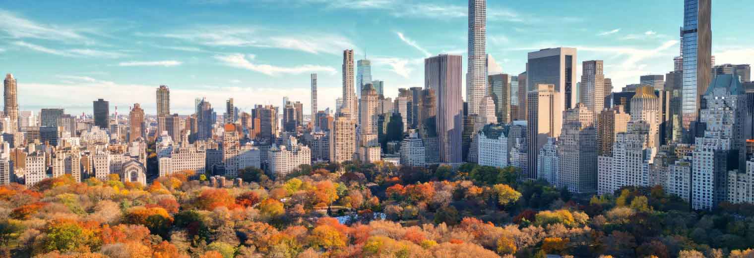 wallypark-airport-parking-fall-deals-inset3 Aerial view of Central Park in New York City during autumn, with colorful fall foliage and tall skyscrapers—an iconic scene that makes NYC one of the best cheap fall travel destinations under a blue sky with scattered clouds.